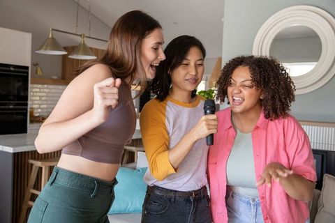 Diverse Women Singing and Enjoying Karaoke at Home Gathering
