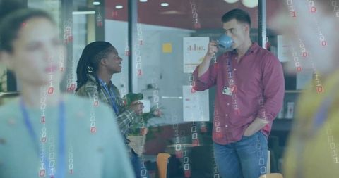 Coworkers chatting over coffee in modern office breakout with glass walls and greenery