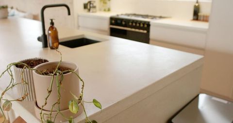 Minimalist stone kitchen island with trailing plants and modern setup