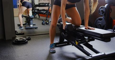 Woman performing one-arm dumbbell row on adjustable bench for strength training