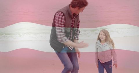 Father playing with daughter on beach walking by waves smiling with soft red band overlay