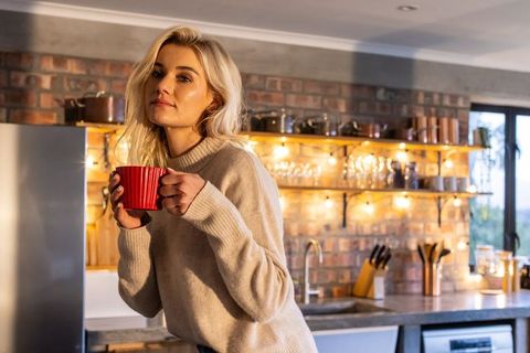 Cozy morning woman holding red mug in rustic modern brick kitchen