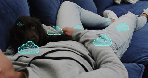 Asian man relaxing with dog on navy sofa with turquoise cloud overlays for cozy lifestyle