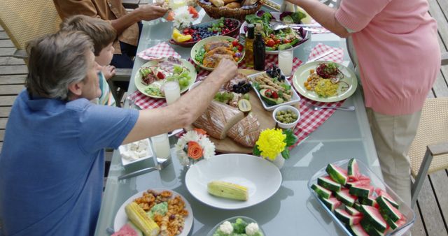 Group of friends enjoying a summertime meal outdoors with a table full of bright, fresh food and drinks. Perfect for ads and content about summer activities, social gatherings, and outdoor living.