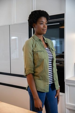 Smiling African American Woman Standing in Minimalist Kitchen