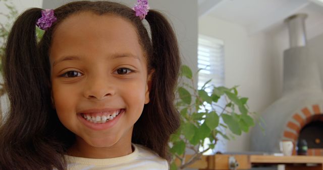 Front view of cute little black girl looking at camera in a comfortable home. Portrait of smiling girl 4k