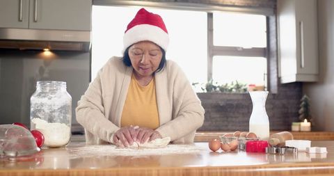 Senior Asian Woman Baking Traditional Holiday Treats in Cozy Kitchen