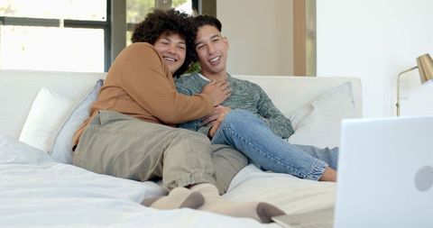Diverse Male Partners Relax on Bed with Laptop
