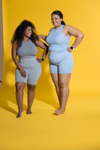 Diverse plus-size women posing in blue activewear on vibrant yellow backdrop