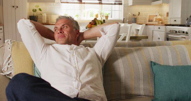 Happy caucasian man sitting on sofa in living room, relaxing - Download Free Stock Photos Pikwizard.com