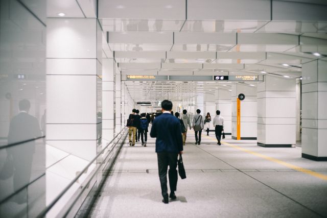 This image shows a group of commuters walking through a modern underground station, reflecting a busy urban lifestyle. It is ideal for articles or blogs related to public transportation, daily commutes, city living, or modern infrastructure. It can also be useful for websites or magazines focusing on travel tips, urban development, or office life.