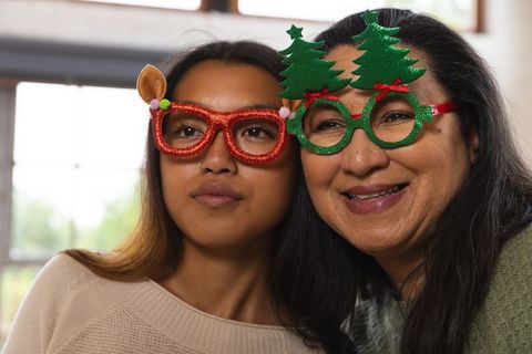 Cheerful Mother and Daughter in Holiday Glasses by Window