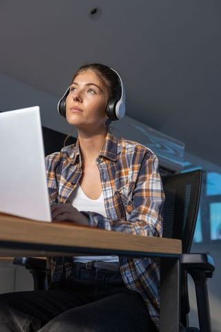 Woman Focused on Work in Modern Home Office with Laptop and Headphones