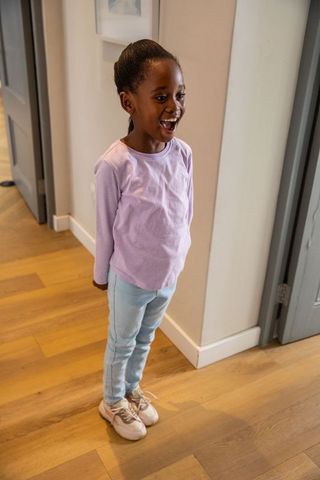 African american girl standing in hallway wearing lavender top and untied sneaker lace