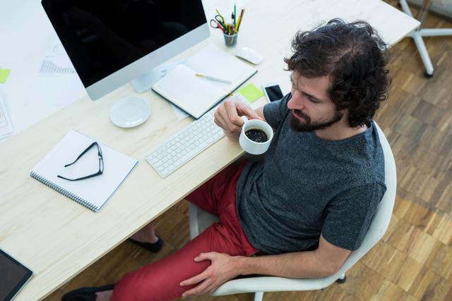 Male graphic designer having black coffee in office