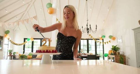 Woman cutting cake at festive 21st birthday celebration