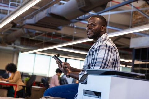 Smiling Professional with Tablet in Modern Open Workspace