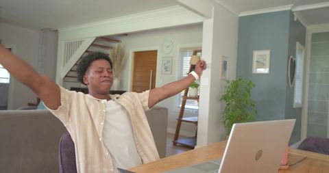 African american man stretching at home workspace with laptop and calm minimalist interior