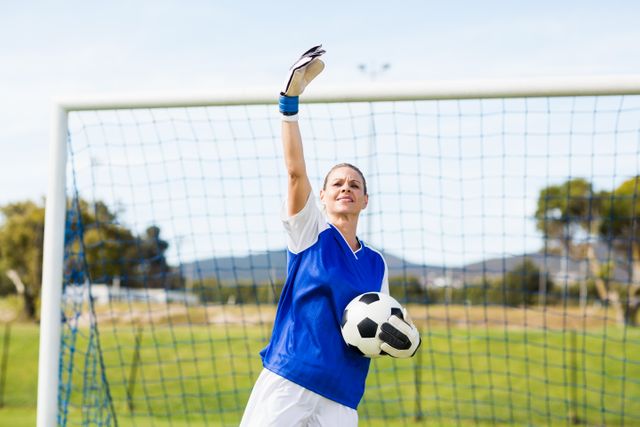 Female goalkeeper holding a ball and gesturing during a game