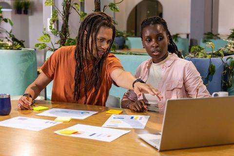 Young creative team analyzing marketing charts on laptop in modern coworking space