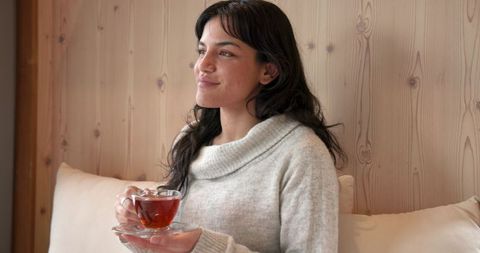 Woman Relaxing with Cup of Tea in Cozy Teahouse