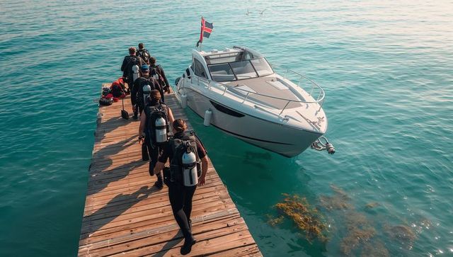 Wetsuit divers walking along wooden pier toward motorboat carrying scuba tanks and bcds
