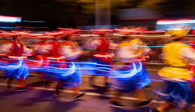 Parading dancers moving with glowing led costumes, vibrant motion blur at night festival