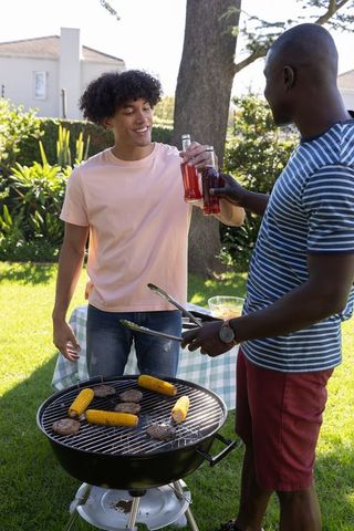 Friends Grilling Burgers at Backyard Barbecue on Sunny Day