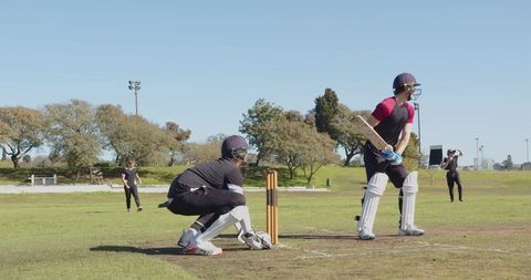 Cricketers in action at wicket on sunny outdoor field