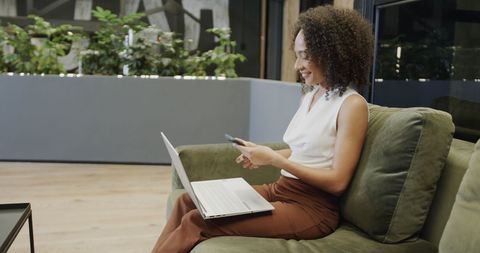 Businesswoman Balancing Laptop and Smartphone in Office Lounge