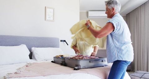 Senior Lesbian Couple Packing Luggage in Bedroom For Vacation