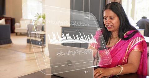 Indian professional woman working on laptop with holographic analytics dashboard in lounge
