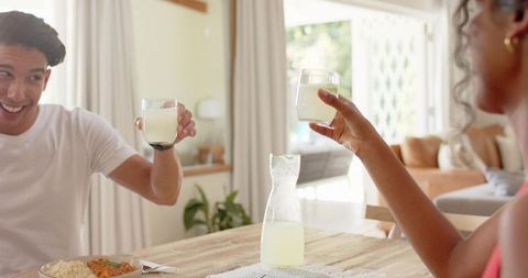 African american couple toasting with lemonade at sunlit wooden dining table cozy brunch