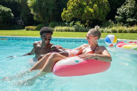 Couple Enjoying Sunny Day in Backyard Pool with Inflatable Float