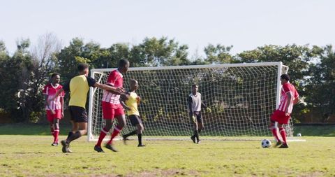 Diverse Soccer Players Competing Near Goal in Sunshine