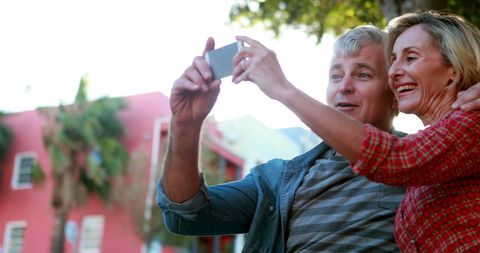 Joyful Older Couple Taking Selfie Outdoors on Sunny Day