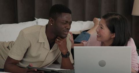 Couple Collaborating on Laptop While Relaxing on Bed