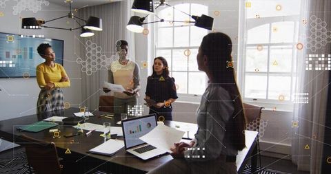 Women collaborating in boardroom reviewing analytics reports with digital data overlays