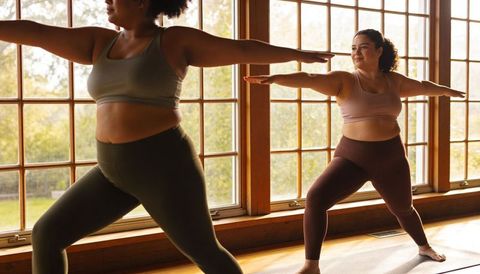 Plus-size women practicing morning yoga in sunlit wooden home studio promoting body positive fitness