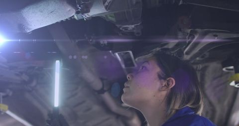 Female Mechanic Inspecting Vehicle Undercarriage with Light
