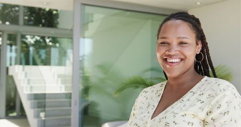 Smiling young woman enjoying sunny outdoors with modern architecture