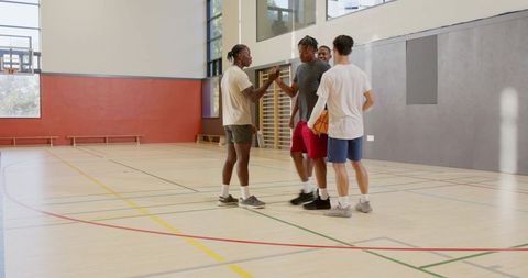 Multiracial teammates greeting and planning before pickup basketball game in indoor gym
