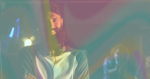 Bearded DJ Enjoying Nightclub Performance with Vibrant Lighting