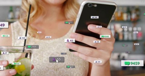 Young woman using smartphone at bar with social media notifications overlay and cocktail