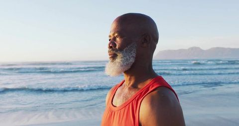 Man Contemplating Ocean in Red Tank Top at Dawn
