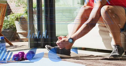 Man tying running shoes in sunlit living room with smartwatch tracking fitness