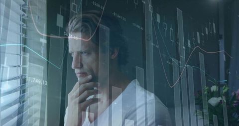 Contemplating businessman gazing through blinds with overlaid stock market charts