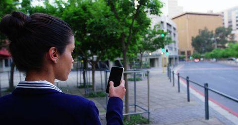 Woman checking smartphone in city street using mobile technology