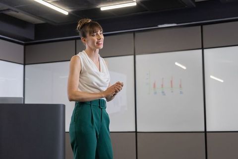 Female executive presenting confidently in modern conference room at podium with chart