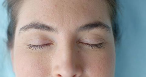 Closeup of woman resting with closed eyes showing eyelashes, skin texture and calm